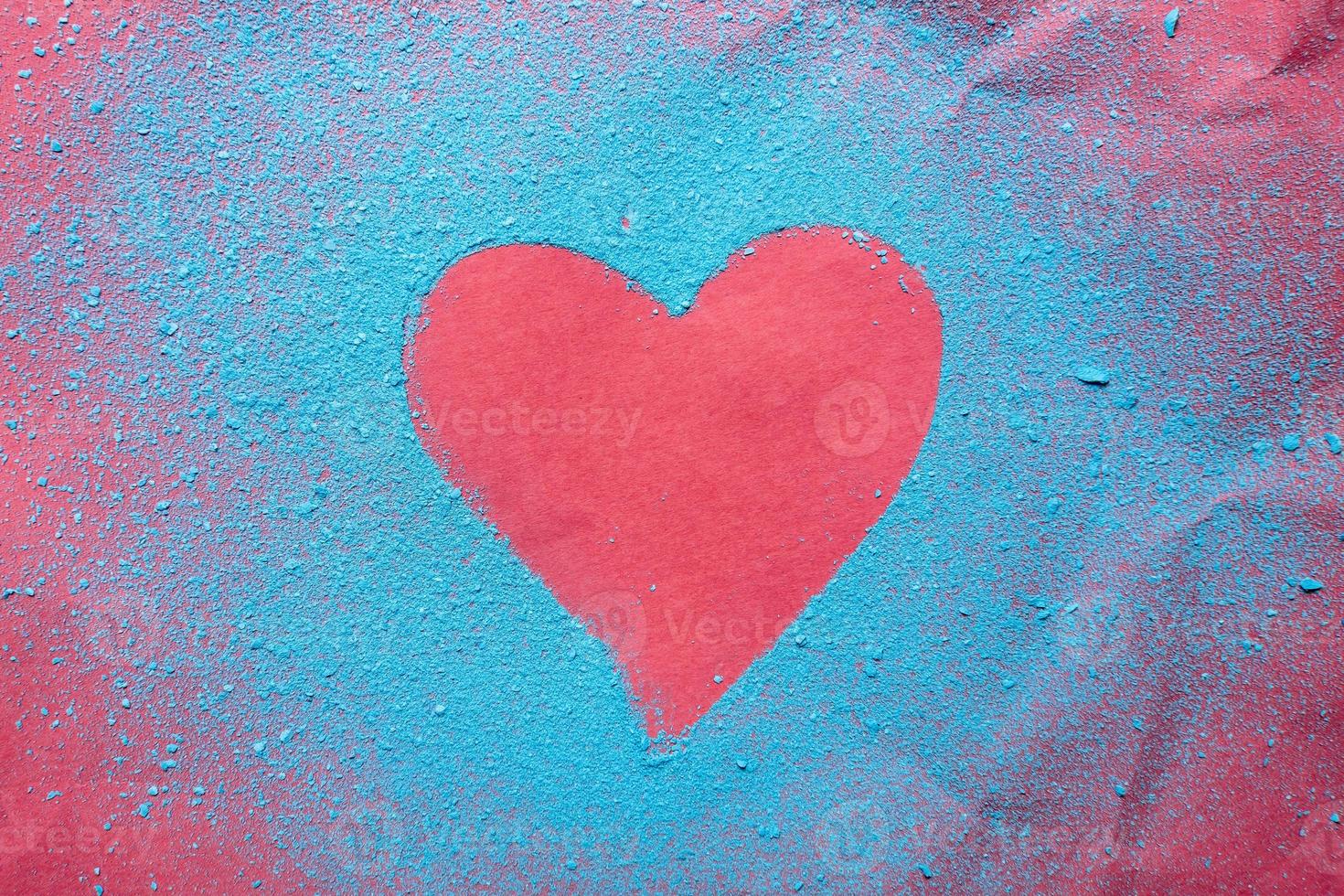 Valentine's Day. Red heart - a symbol of love sprinkled with bright blue powder, on a bright textured background. Romantic concept.. photo