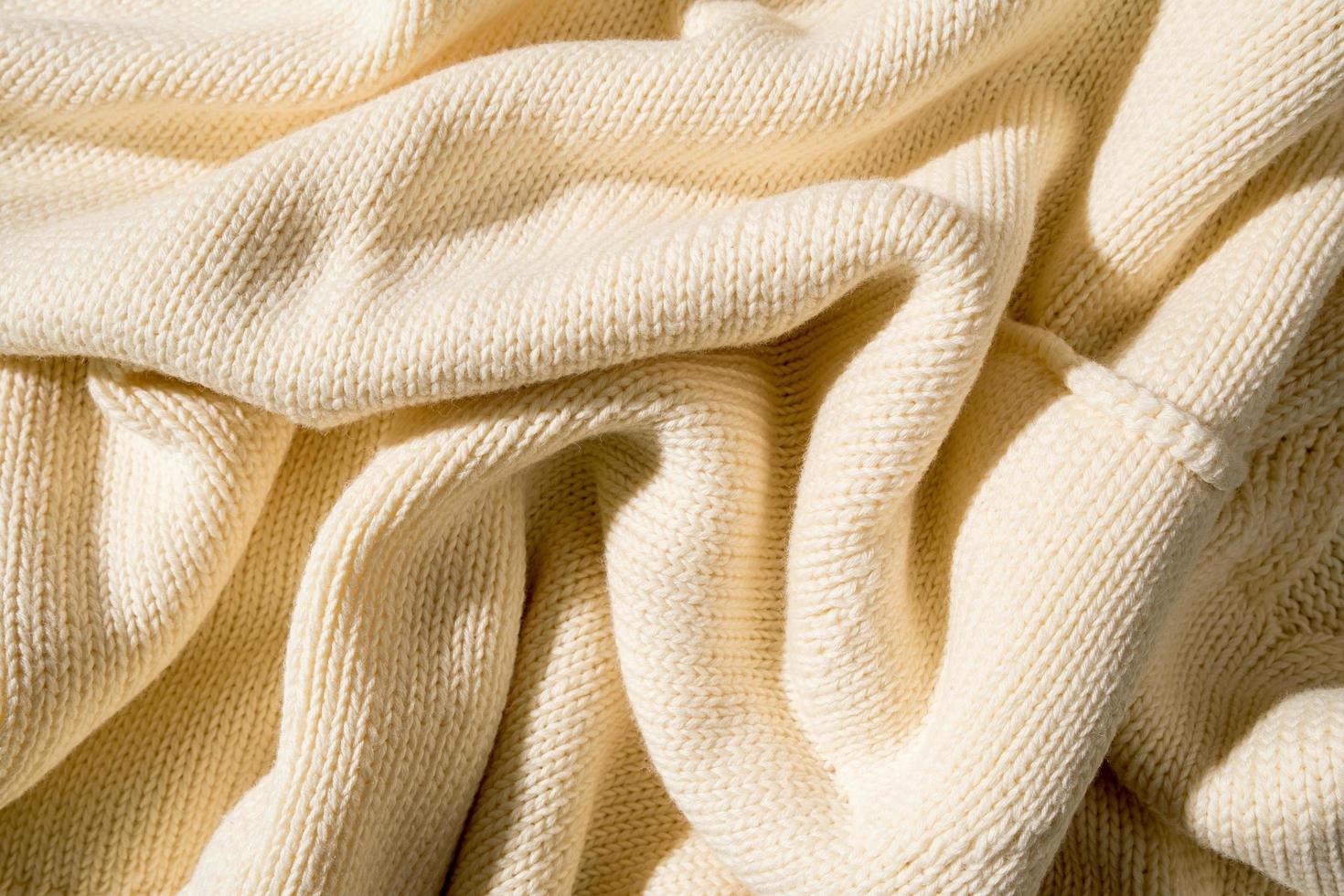 Knitted wrinkled texture in yellow color, top view, abstract background. photo