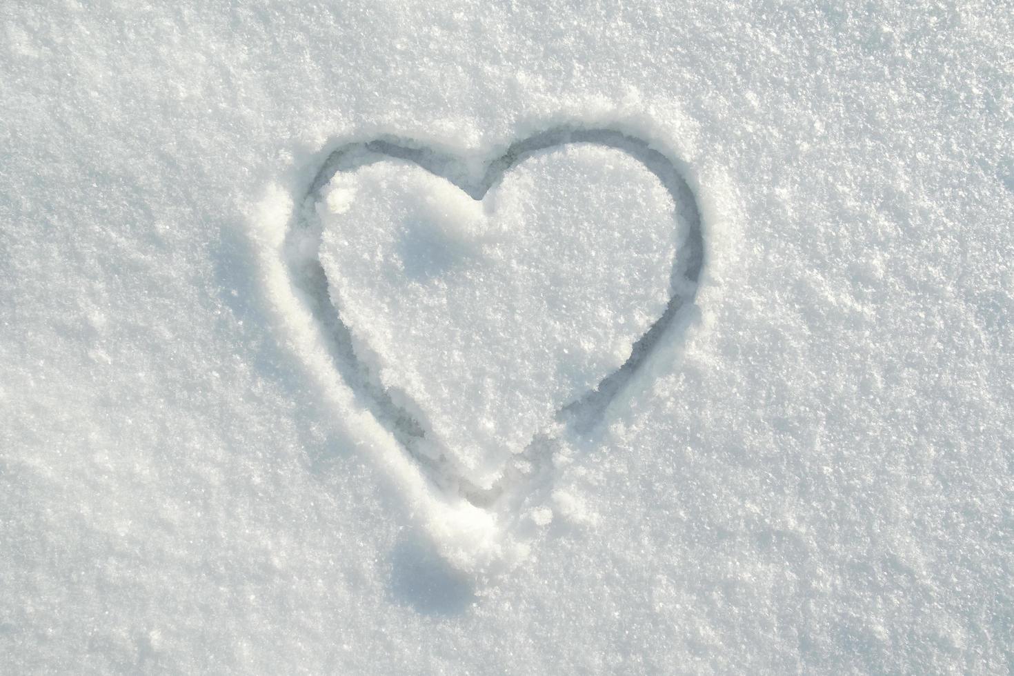 símbolo del corazón dibujado en la nieve, en un soleado día de invierno. romance. día de San Valentín. copie el espacio. foto