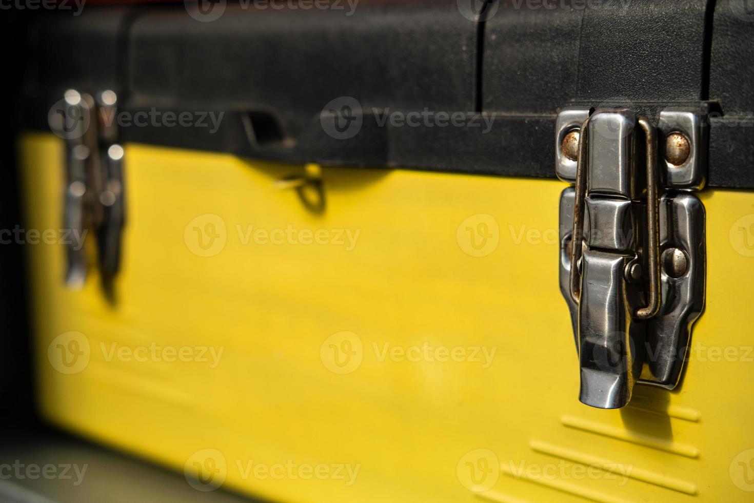 Yellow-black toolbox is closed with two metal locks. photo