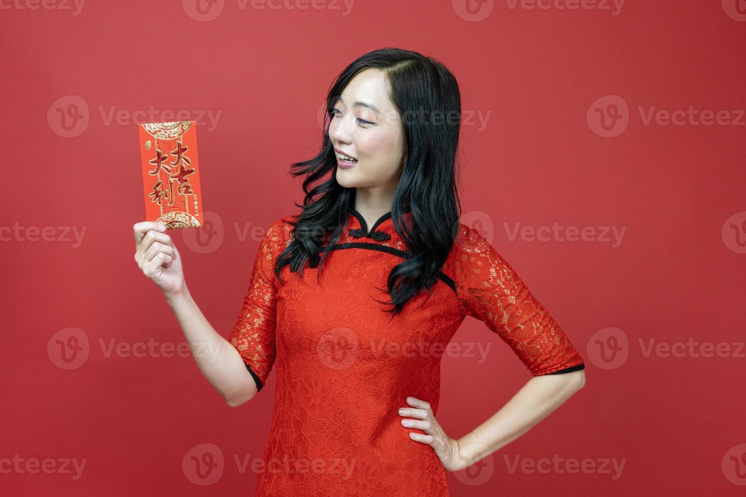 Asian woman holding red money fortune envelope blessing Chinese word which means May you have great luck and great profit isolated on red background for Chinese New Year celebration concept photo