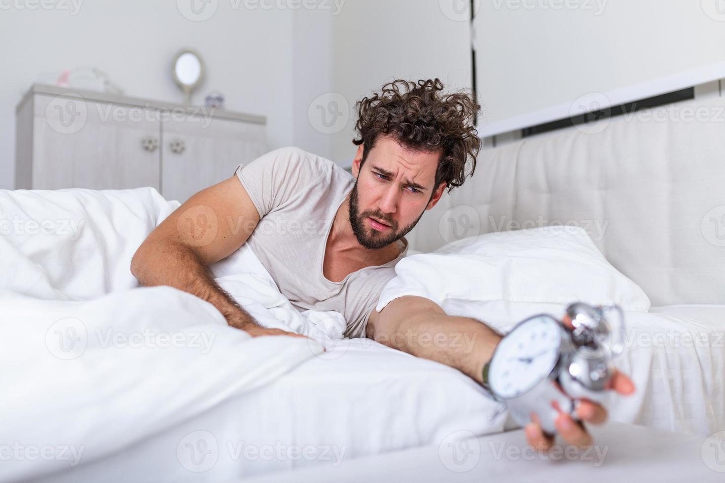 Hate this noise. Problem with early morning awakening. Get up early. Man bearded hipster sleepy face waking up. Daily schedule for healthy lifestyle. Alarm clock ringing. photo