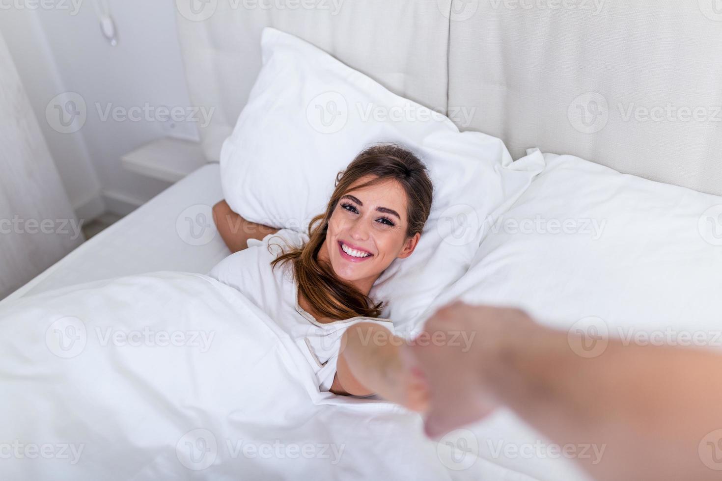 Honeymoon relationship guy date concept. POV view of attractive pretty charming lovely cute sweet lady holding by hand leads to bed her man. girl lying on a bed and holding a guy's hand photo