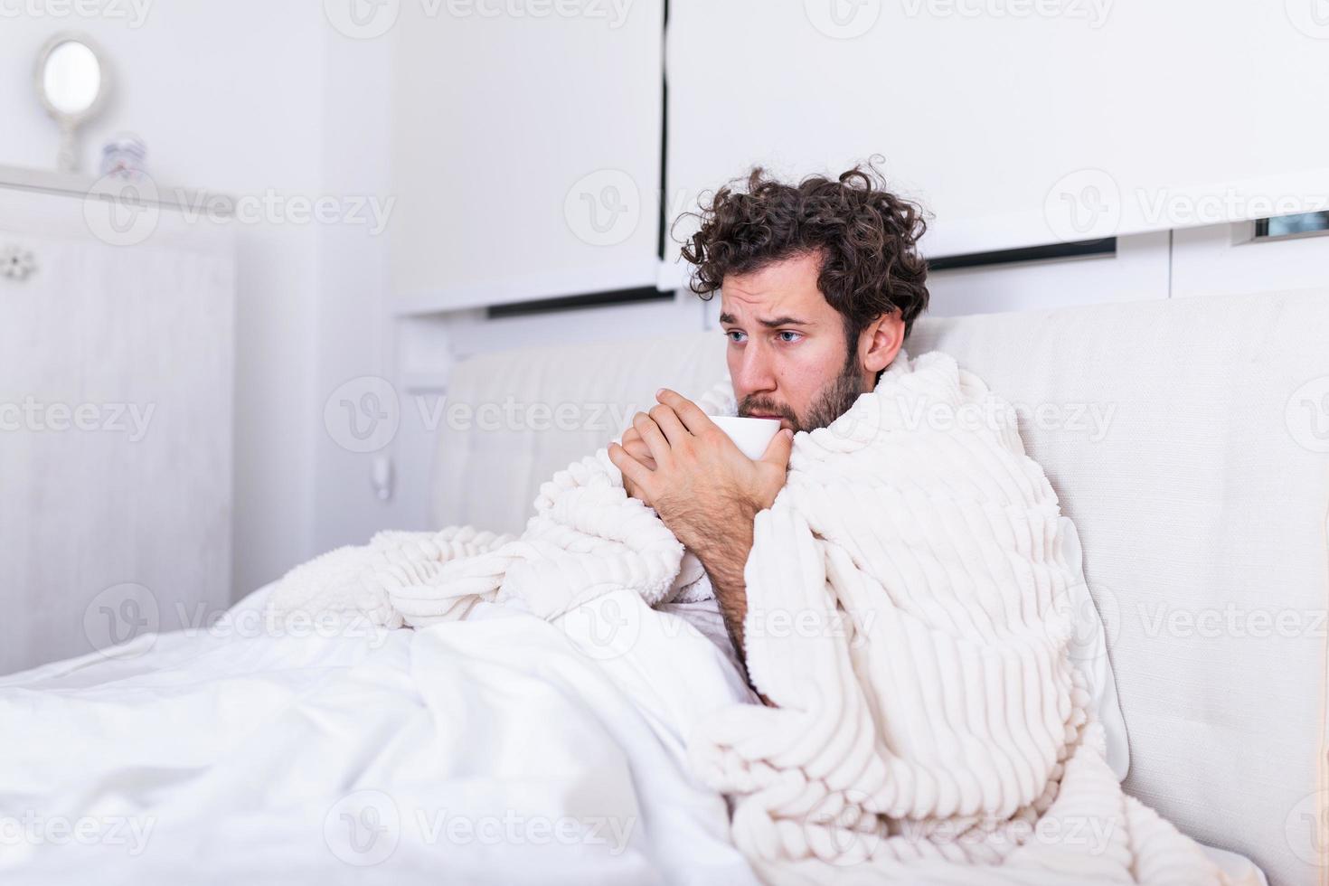 Sick day at home. Handsome Man has fever and common cold. Cough. Closeup Of Young Man Caught Cold Or Flu Illness. Portrait Of Unhealthy man Feeling Pain In Throat and drinking hot beverage. photo