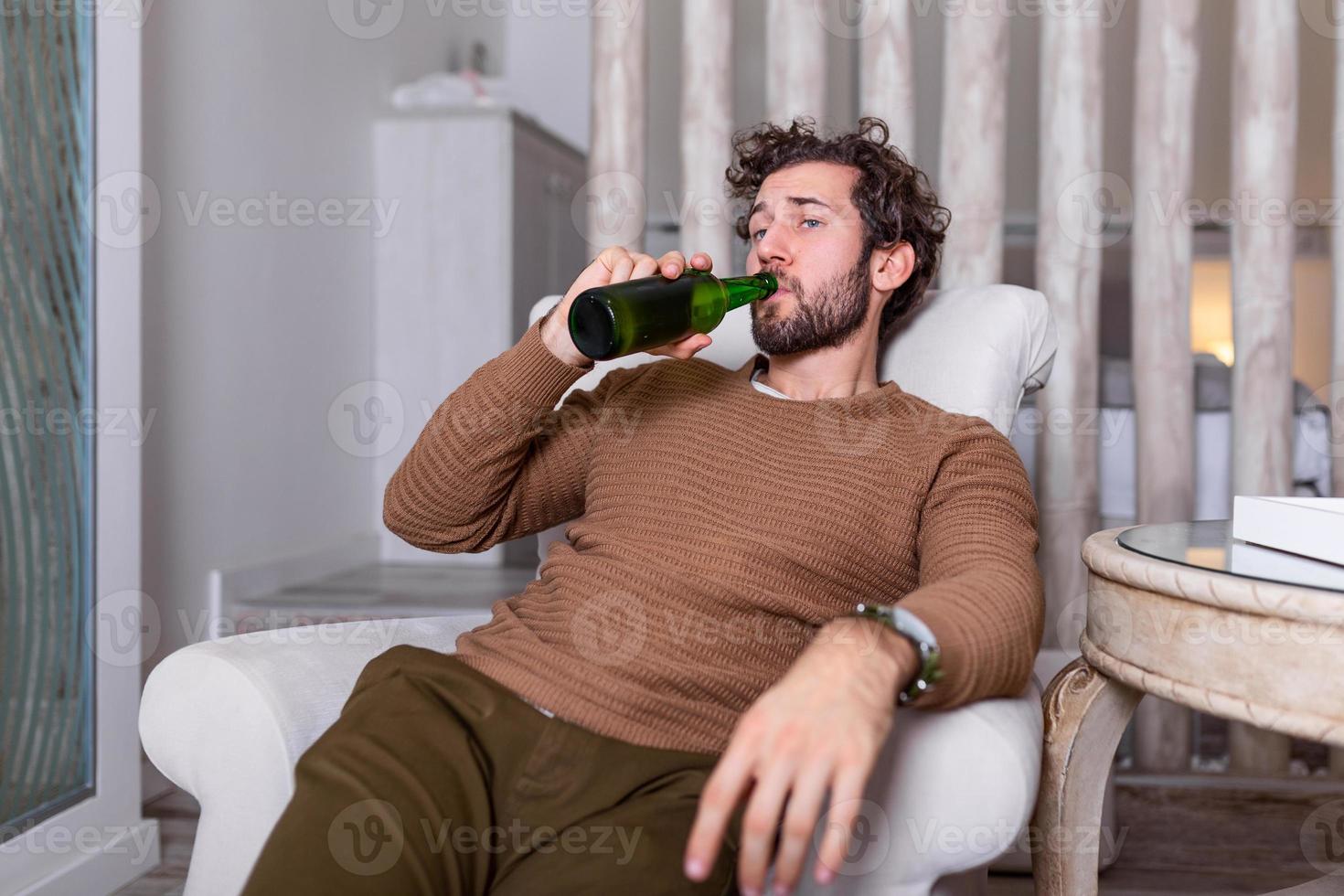 Sad sports fan sitting in an sofa and watching a match on television with his team losing the game . man watching football or soccer game on tv at home and drinking beer photo