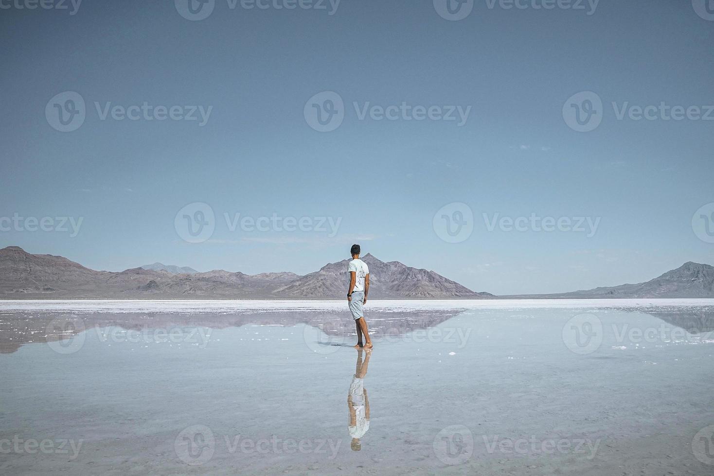 viajero que mira el salar de bonneville y la cordillera que se refleja en el lago foto