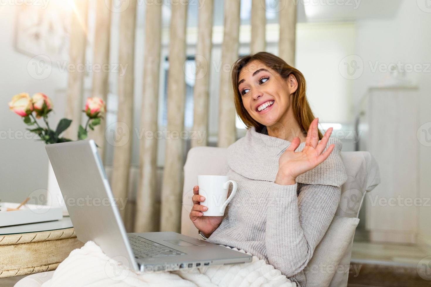 Happy smiling woman sitting on sofa, couch and using laptop at living room at home, watching funny video, learning language, video calling, mother working online photo
