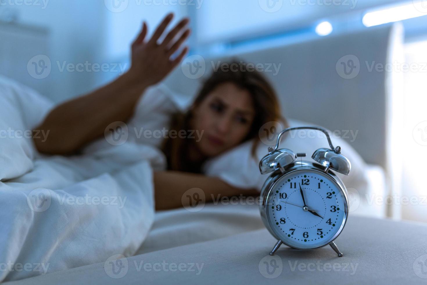 mujer acostada en la cama que sufre de insomnio, insomne y desesperada hermosa mujer caucásica despierta por la noche sin poder dormir, sintiéndose frustrada y preocupada sufriendo de insomnio en el trastorno del sueño foto