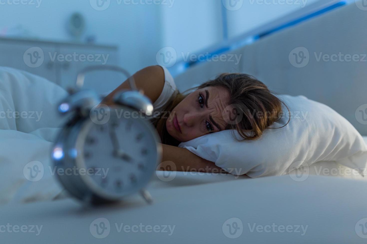 mujer con insomnio acostada en la cama con los ojos abiertos. chica en la cama que sufre insomnio y trastorno del sueño pensando en su problema por la noche foto