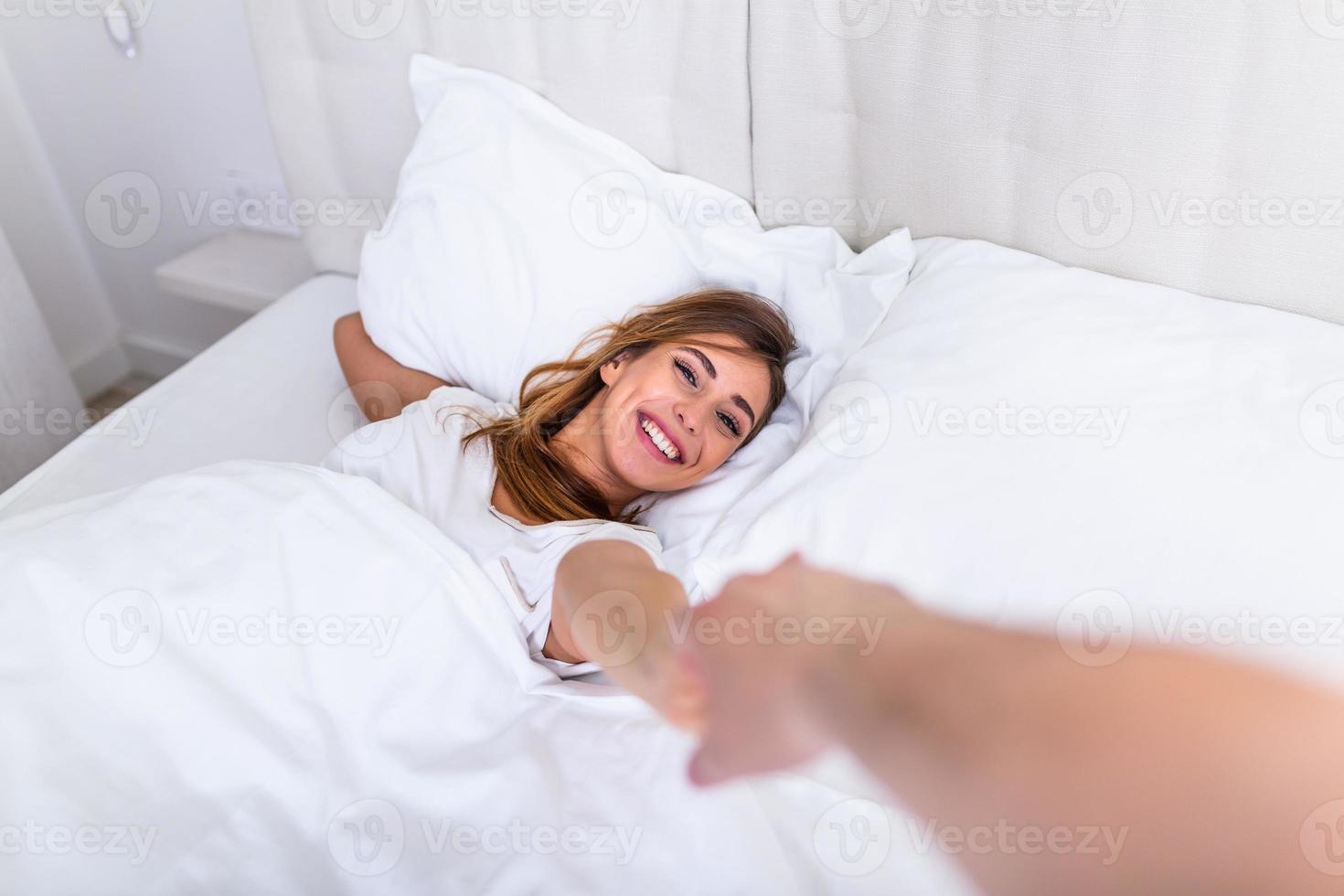 Honeymoon relationship guy date concept. POV view of attractive pretty charming lovely cute sweet lady holding by hand leads to bed her man. girl lying on a bed and holding a guy's hand photo