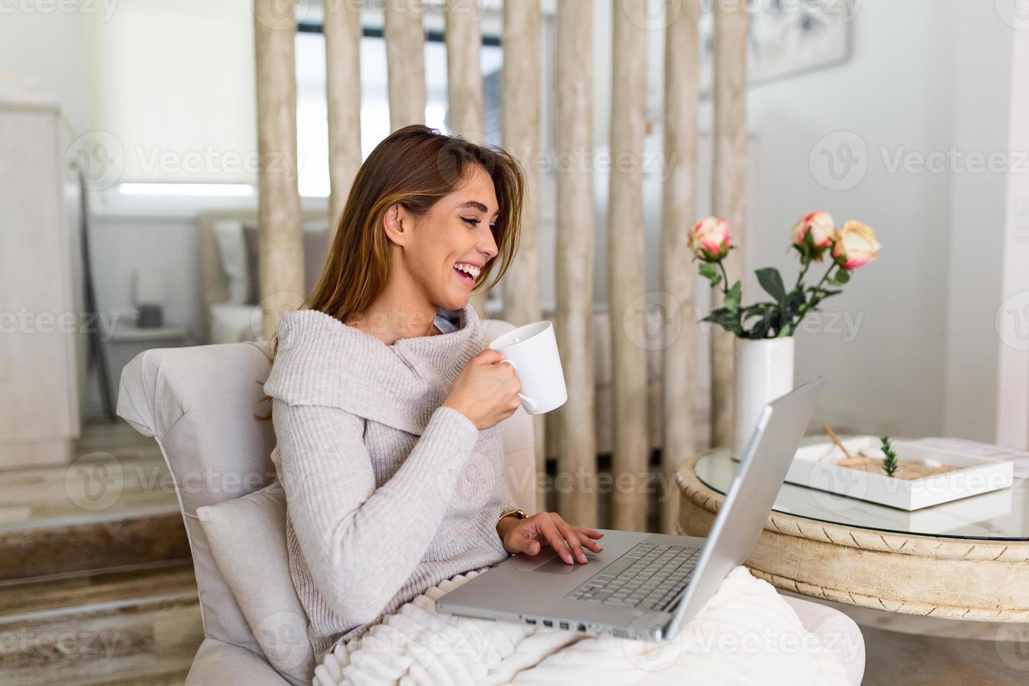 Happy smiling woman sitting on sofa, couch and using laptop at living room at home, watching funny video, learning language, video calling, mother working online photo