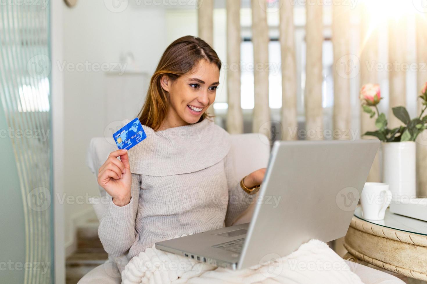 joven hermosa mujer feliz por encontrar artículos de compras para la venta en línea. hermosa chica usando una computadora portátil para comprar en línea en casa foto