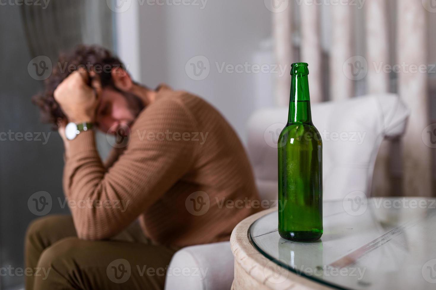Silhouette of anonymous alcoholic person drinking behind bottle of alcohol. Man fighting with alcoholic habits, drink sitting on sofa at home photo