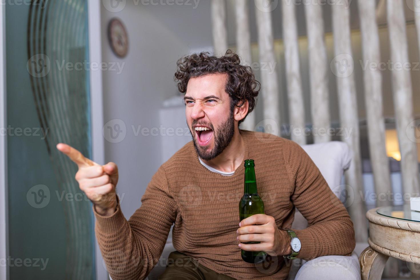 Excited sports fan sitting in an sofa and watching a match on television. leisure, sport, entertainment and people concept - man watching football or soccer game on tv at home and drinking beer photo