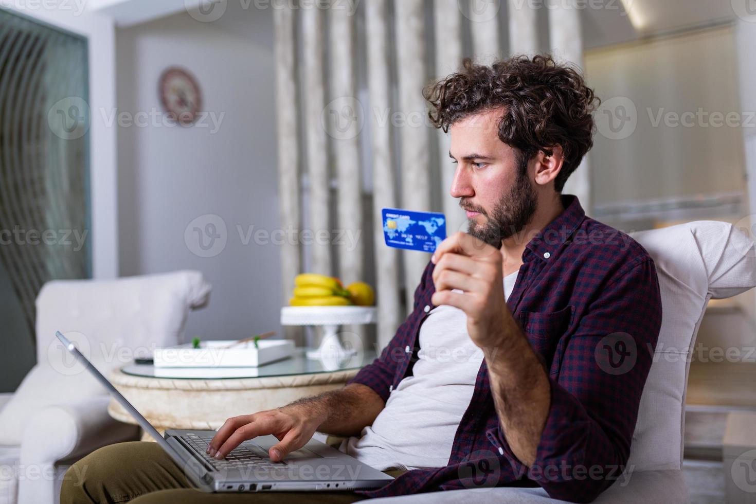 Young Man holding credit card and computer laptop entering data for web-site form, going to pay for online order. People, lifestyle, modern technologies and e-commerce concept photo
