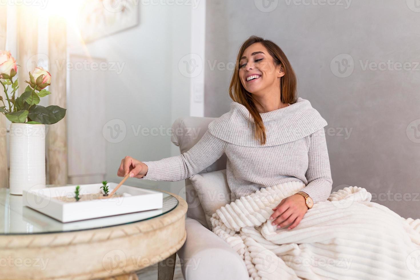 retrato de una hermosa joven usando su jardín zen en casa. encantadora joven mujer sonriente relajándose con su jardín zen y disfrutando de su día foto