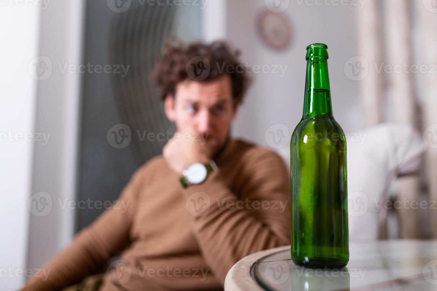 deprimido triste joven adicto que se siente mal bebiendo cerveza solo en casa, estresado frustrado bebedor solitario alcohólico sufre de adicción al alcohol que tiene problemas, concepto de alcoholismo foto