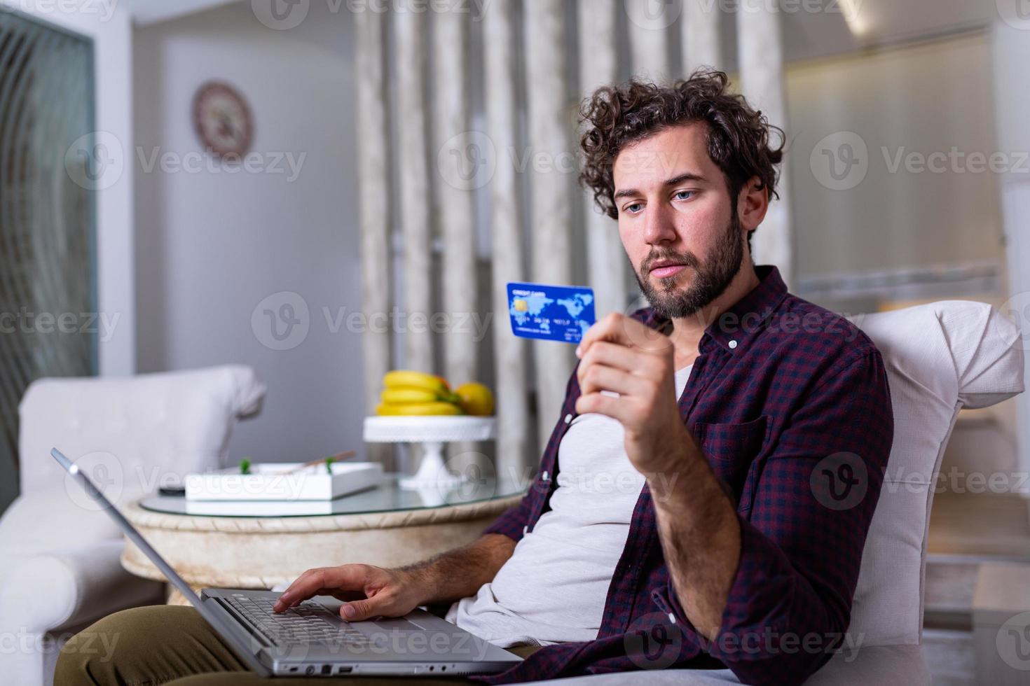 Young Man holding credit card and computer laptop entering data for web-site form, going to pay for online order. People, lifestyle, modern technologies and e-commerce concept photo