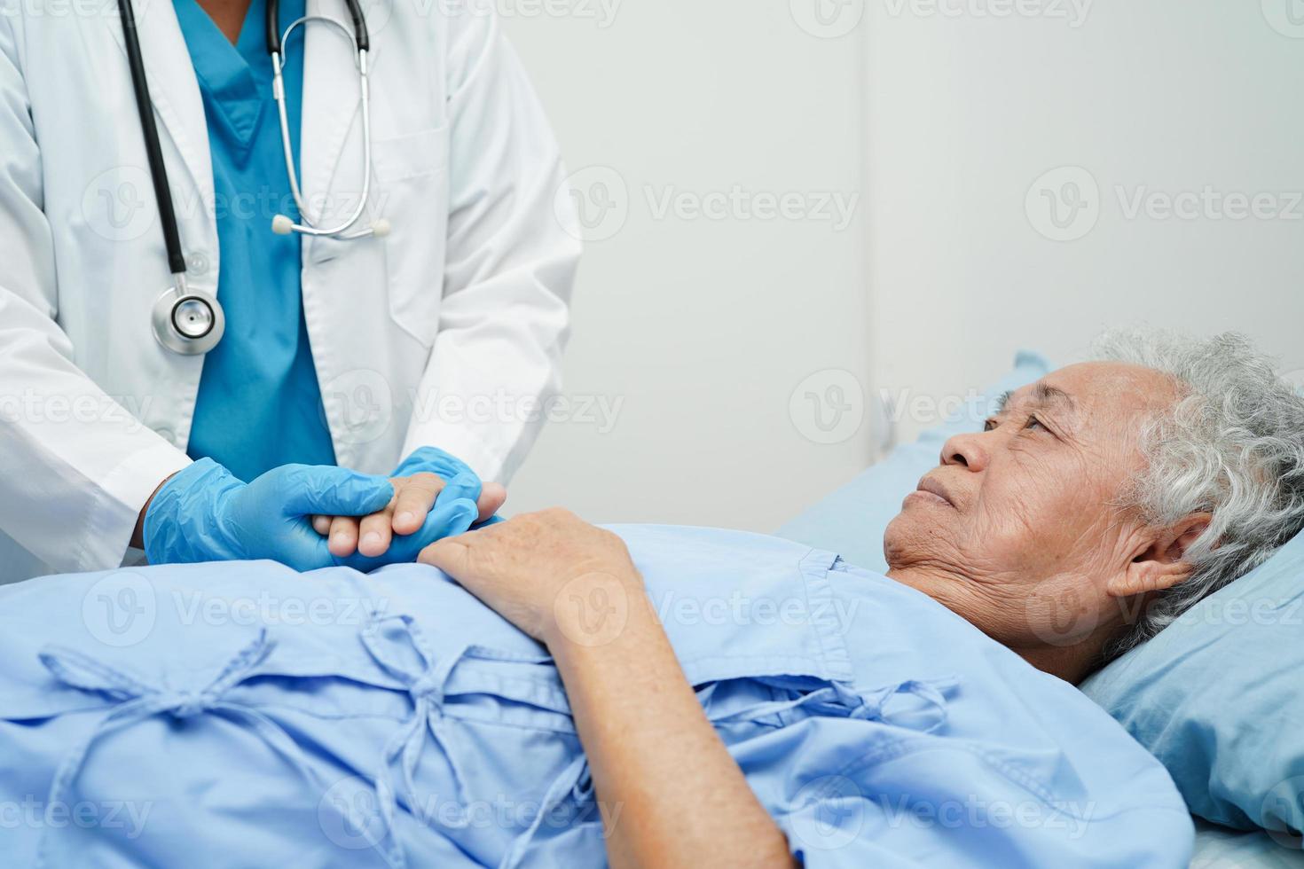 médico tomados de la mano paciente anciana asiática, ayuda y atención en el hospital. foto