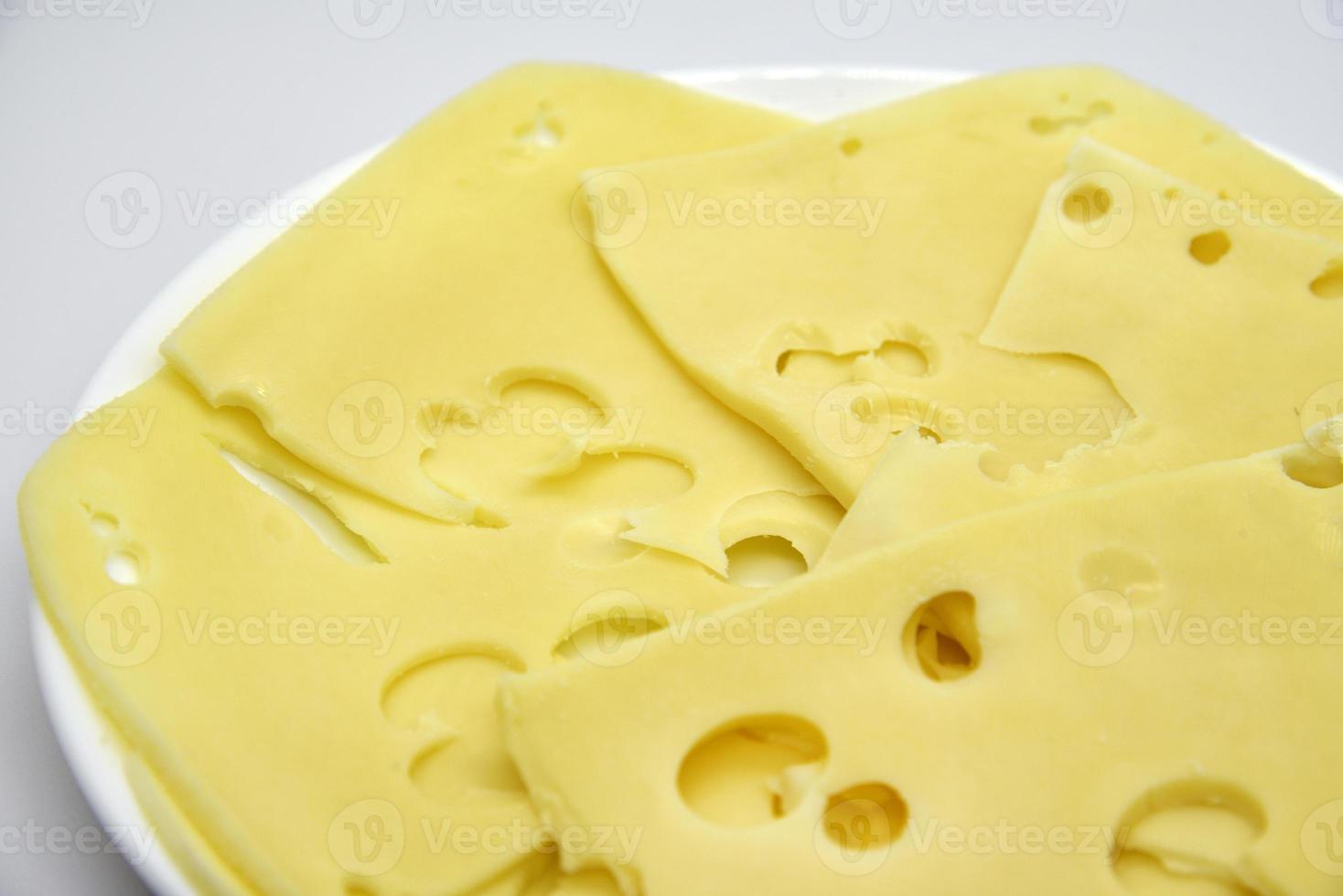 trozos de queso amarillo en rodajas con agujeros en el plato. primer plano de queso picado. deliciosas lonchas de queso. foto