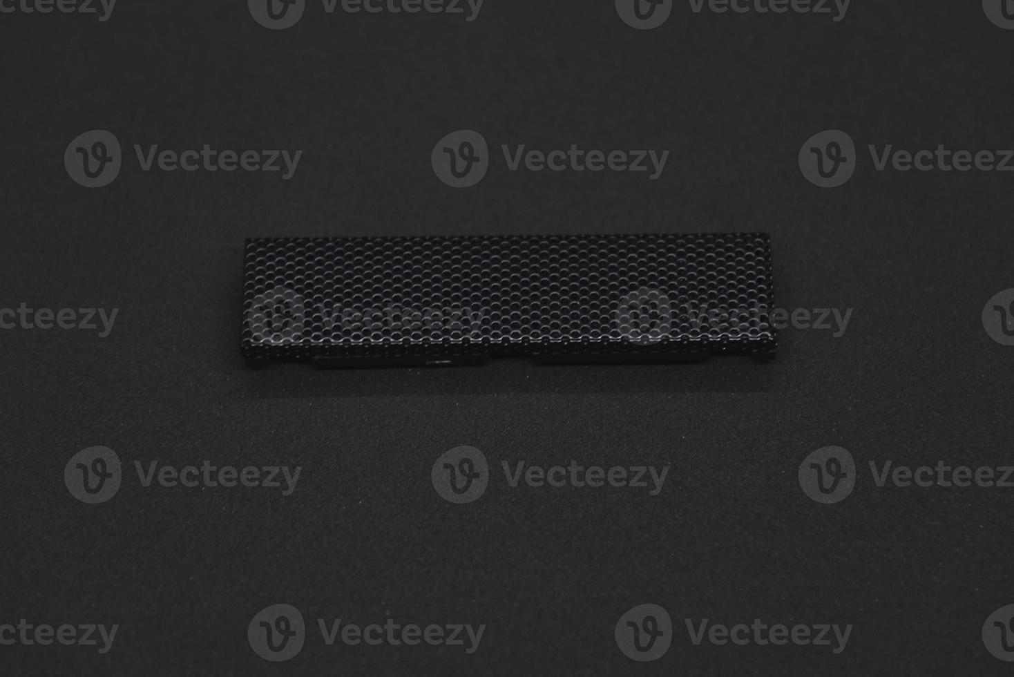The iron panel from the computer. Iron black mesh panel. Metal rectangular panel on a black background. Beautiful iron rectangular black shape. photo