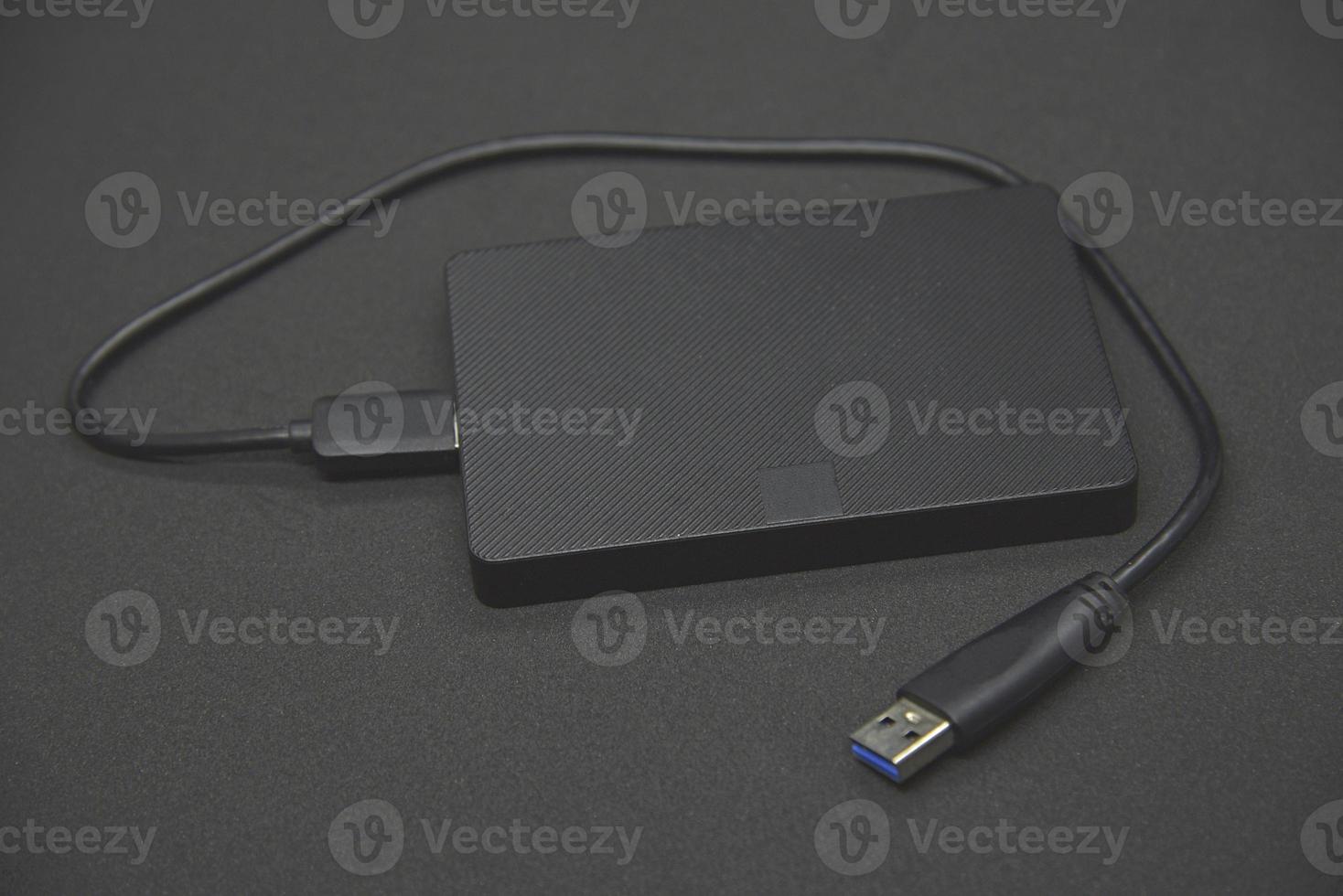 A black portable hard drive on a black background. Information storage. Personal gadget. photo