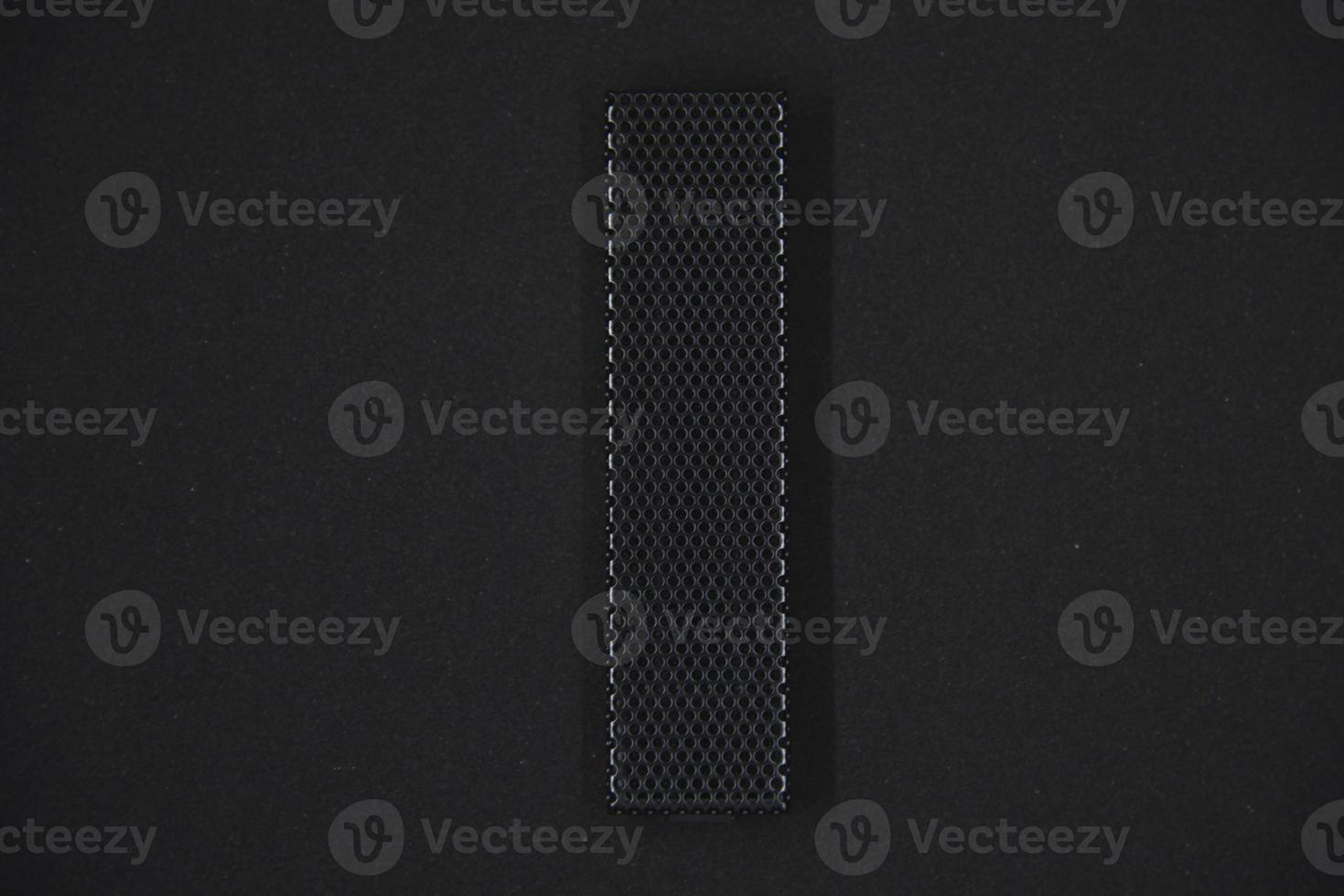 The iron panel from the computer. Iron black mesh panel. Metal rectangular panel on a black background. Beautiful iron rectangular black shape. photo