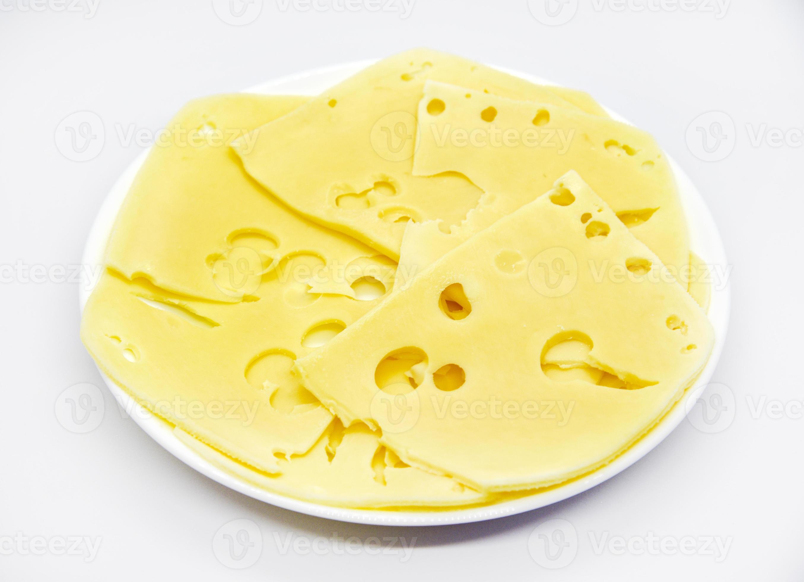 Sliced pieces of yellow cheese with holes on the plate. Chopped cheese