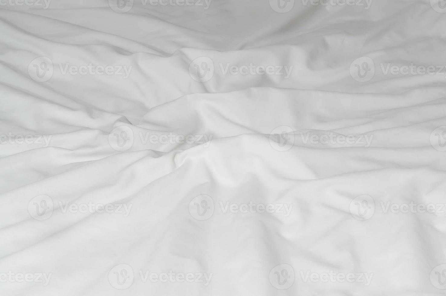 White crumpled or wrinkled bedding sheet or blanket with pattern after guest's use taken in hotel, resort room with copy space, Untidy blanket background texture photo