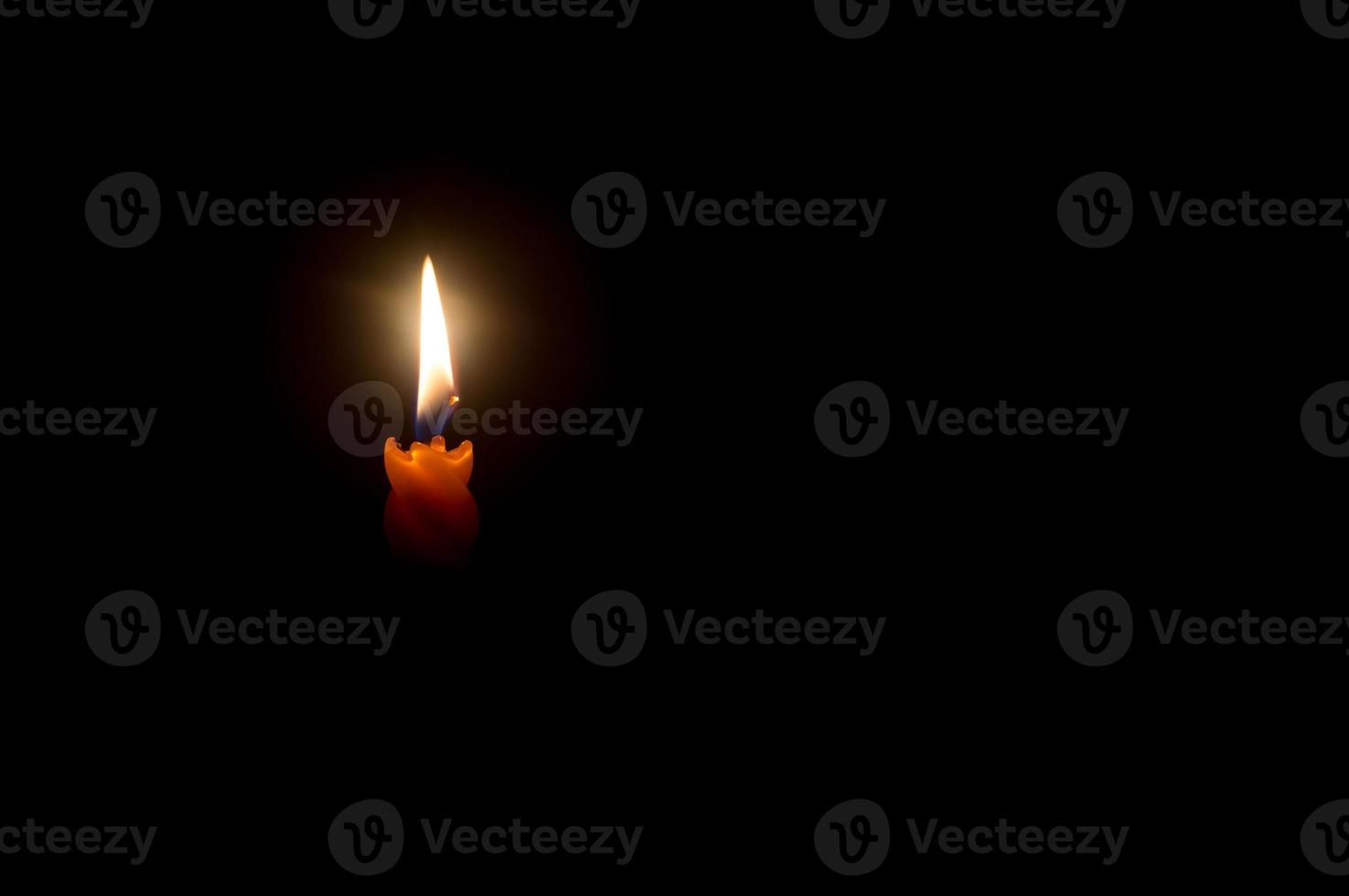 una sola llama de vela encendida o luz que brilla en una hermosa vela espiral naranja sobre fondo negro u oscuro en la mesa de la iglesia para Navidad, funeral o servicio conmemorativo con espacio para copiar foto