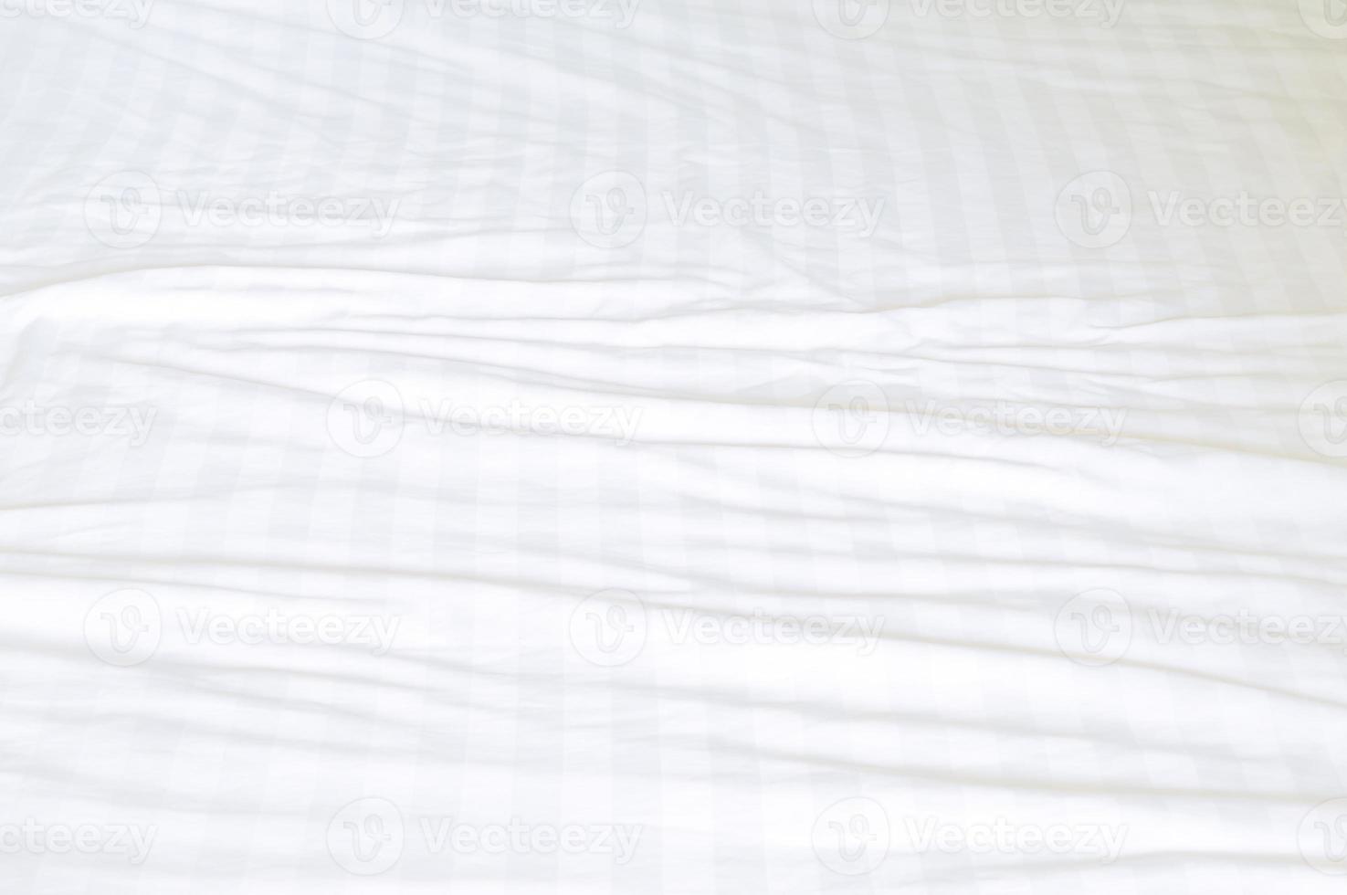 White wrinkled bedding sheet with pattern after guest's use was taken in hotel room with copy space, Untidy blanket background texture photo