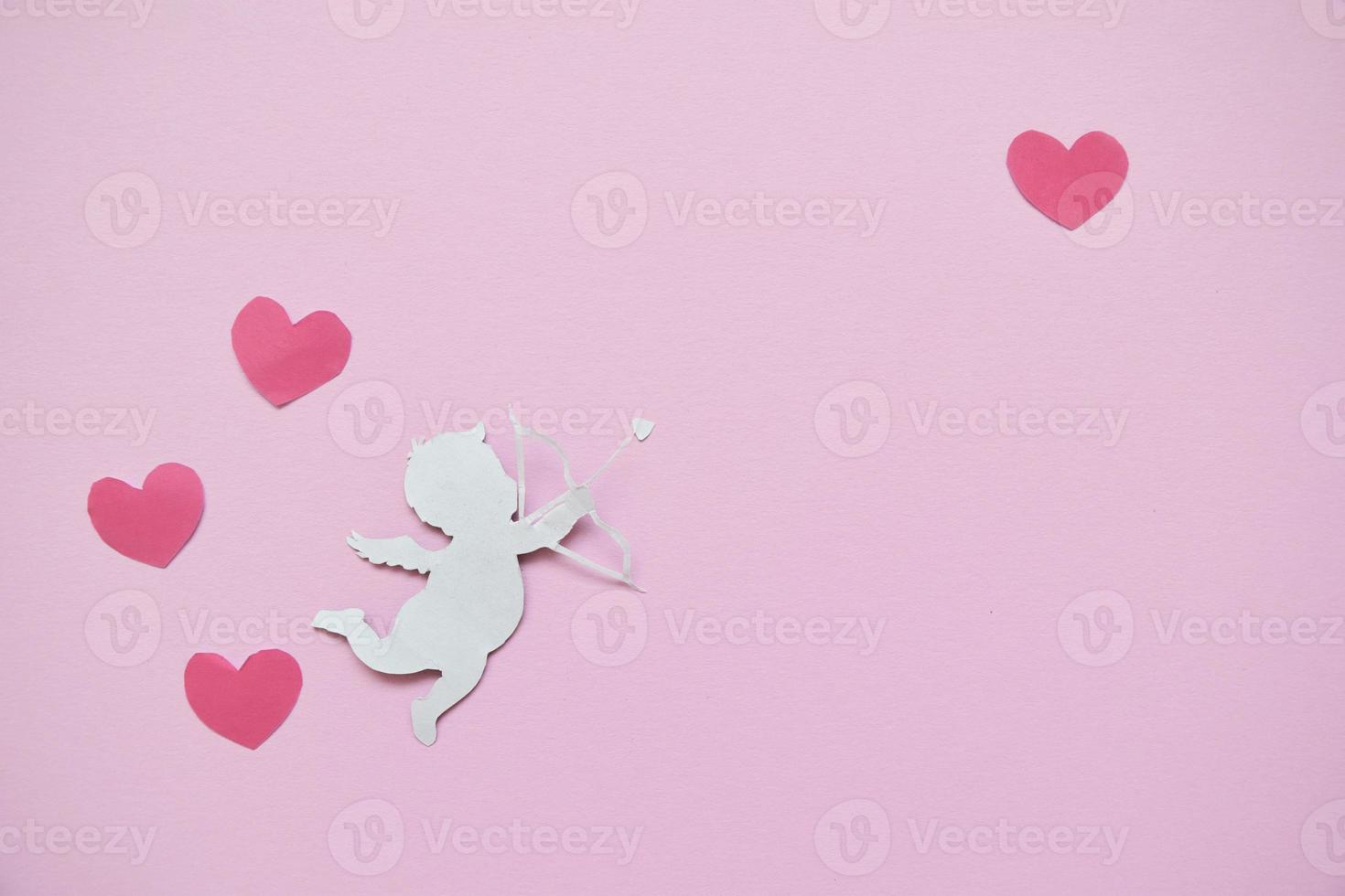 concepto del día de san valentín. corazones de color rojo y cupido apuntando en el corazón sobre fondo rosa. tarjetas del día de san valentín. foto