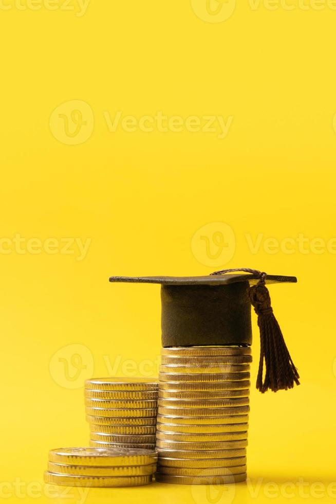 Graduated cap with coins on yellow background. Savings for education concept photo