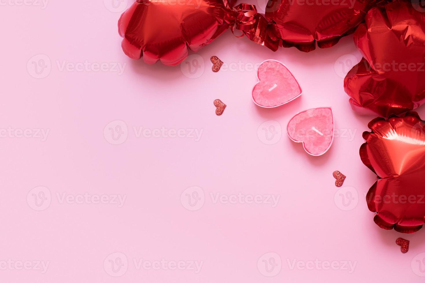 Valentines Day background with copy space and two candels with red heart shape balloons on pink background photo