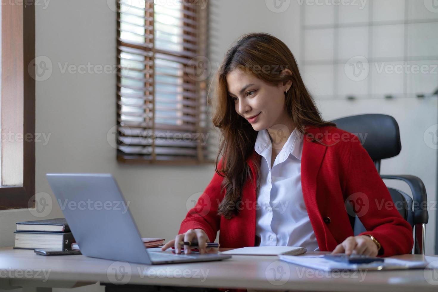 Asian Business woman using calculator and laptop for doing math finance on an office desk, tax, report, accounting, statistics, and analytical research concept photo