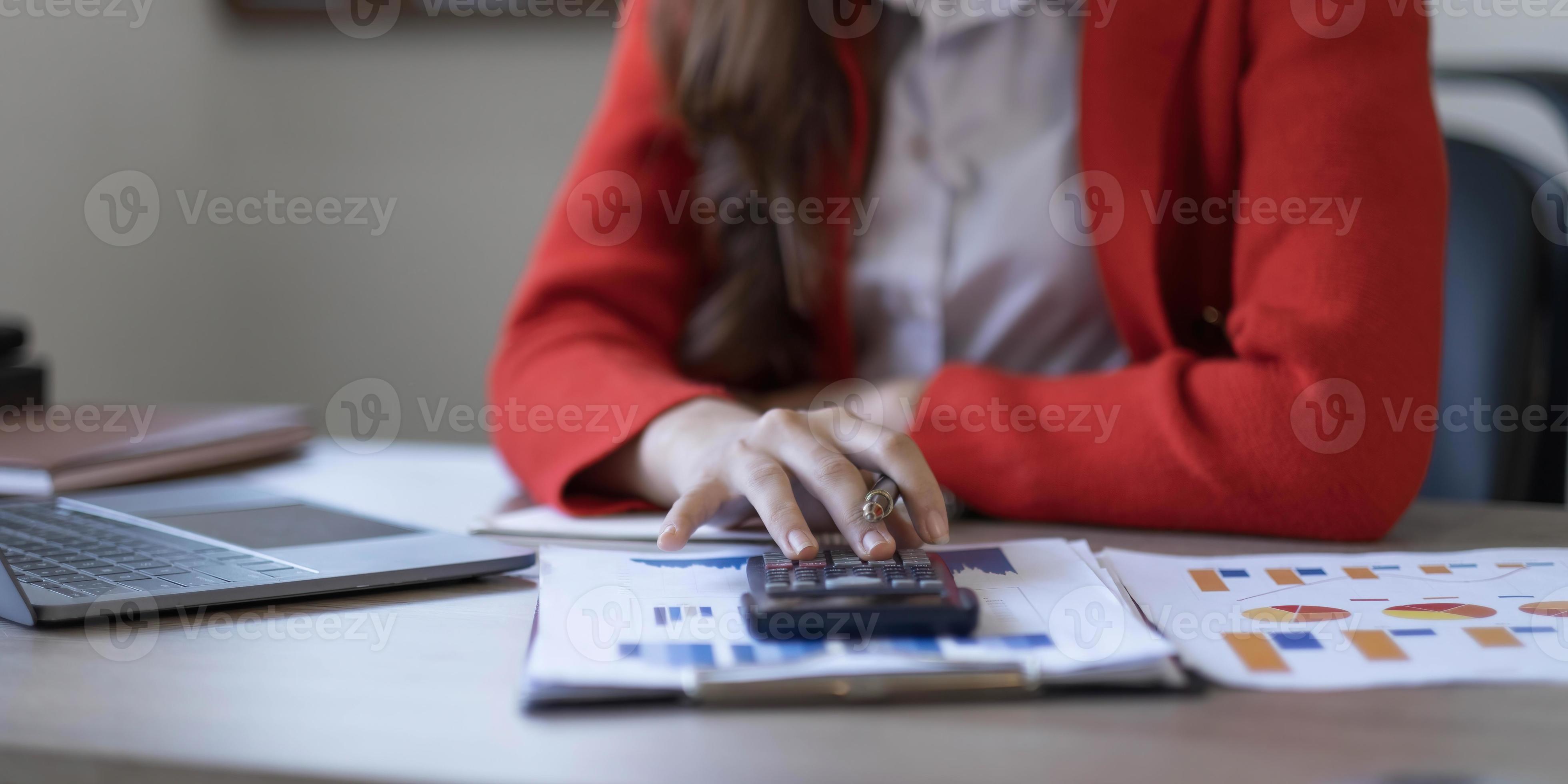 Asian Business woman using calculator and laptop for doing math finance