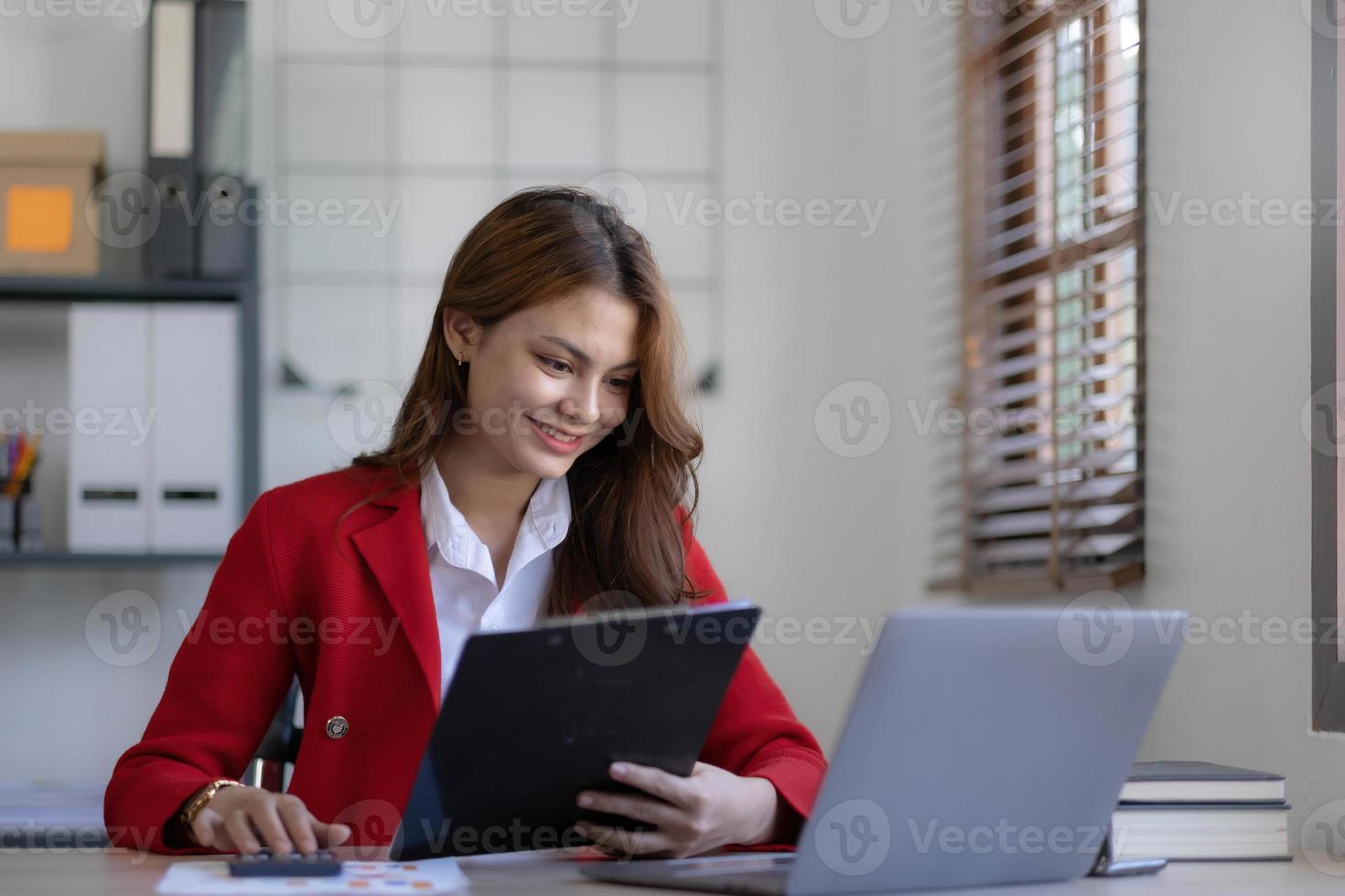 Asian Business woman using calculator and laptop for doing math finance on an office desk, tax, report, accounting, statistics, and analytical research concept photo