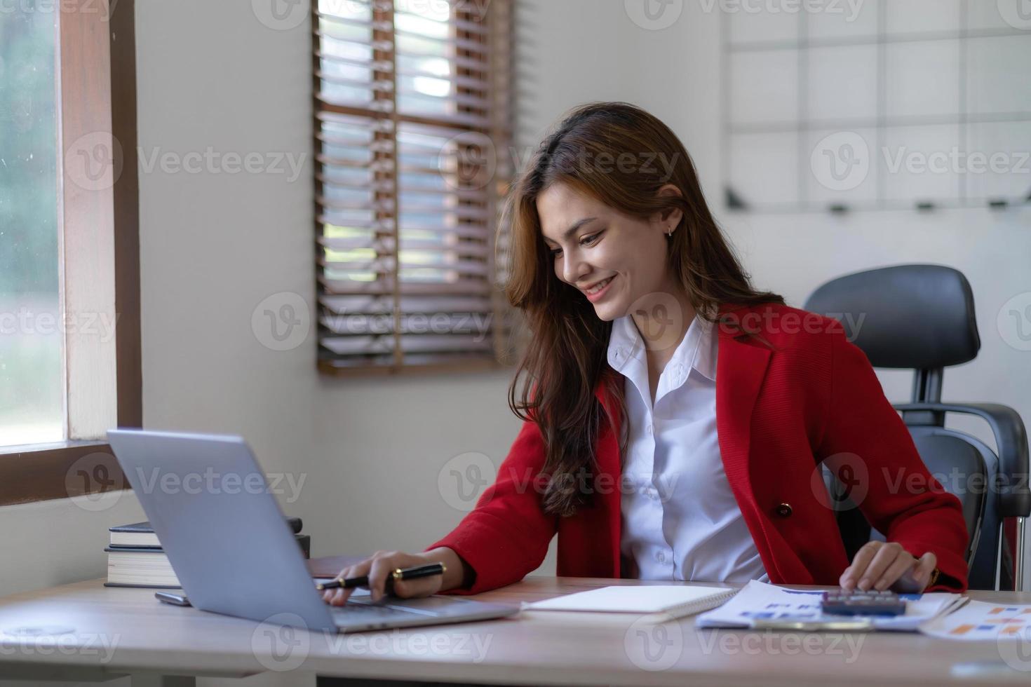 Asian Business woman using calculator and laptop for doing math finance on an office desk, tax, report, accounting, statistics, and analytical research concept photo