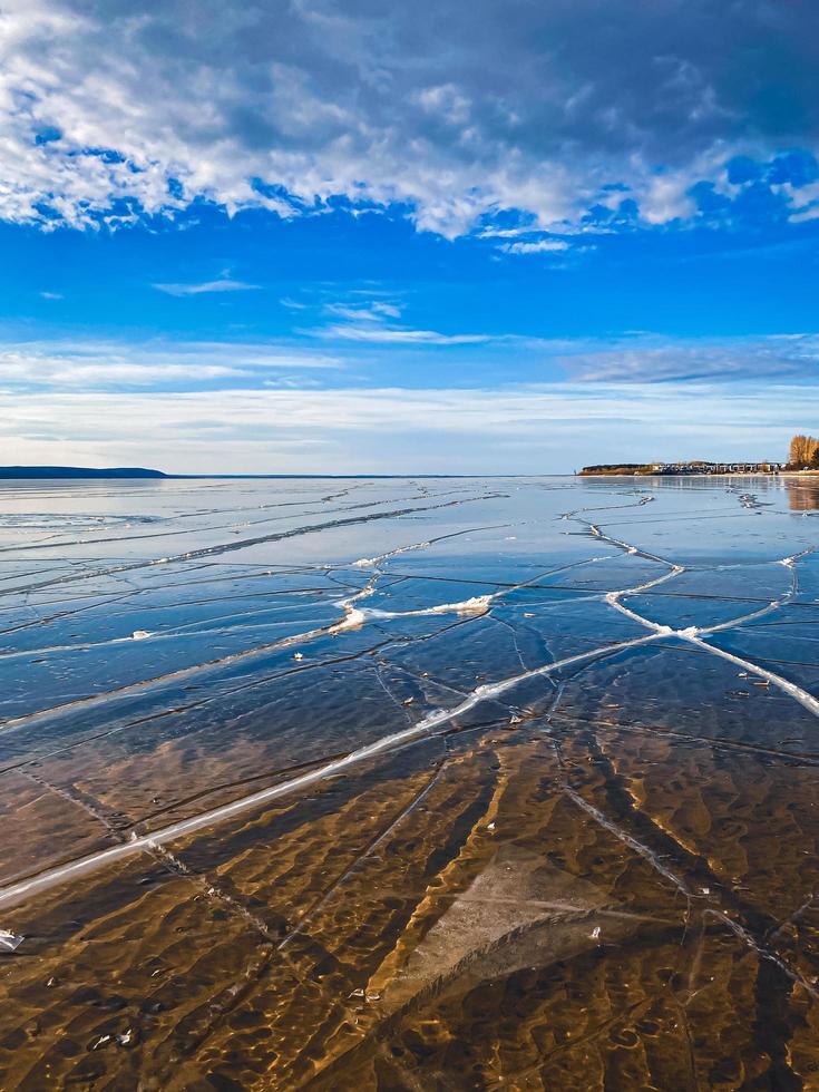 Winter day on frozen lake with transparent ice with cracks. photo