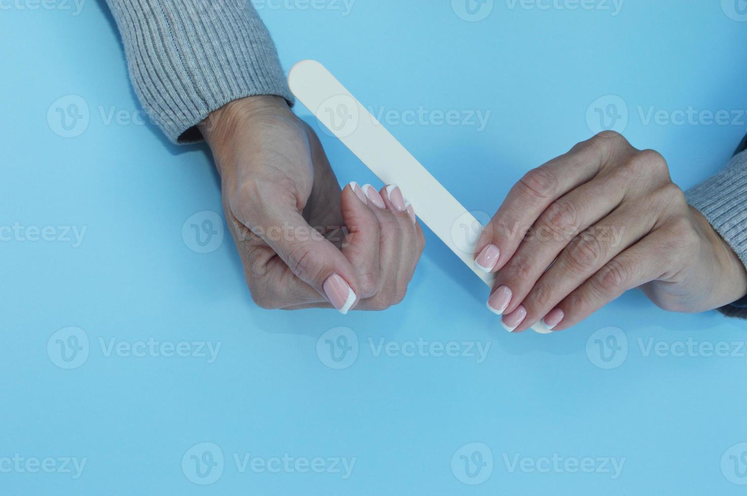 Female hands hold a white nail file and correct manicure. photo