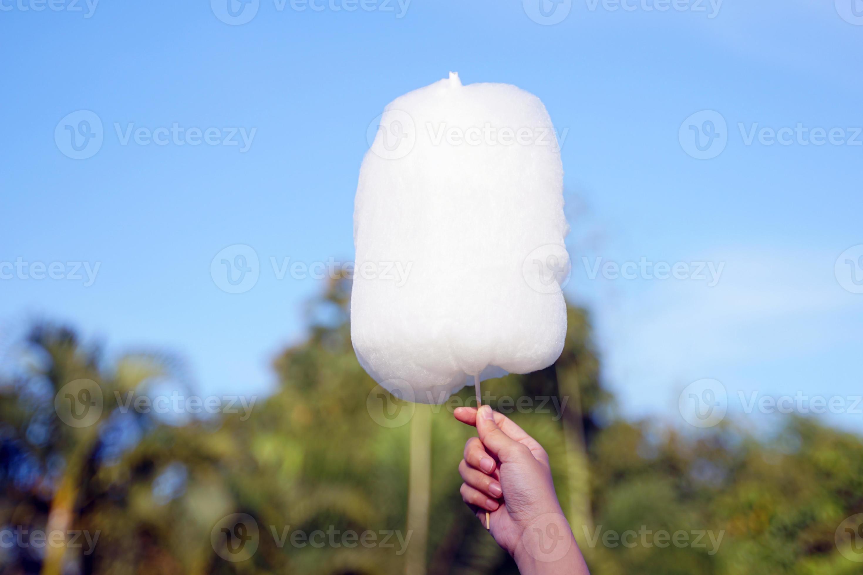 holding white cotton candy on sky background. Cotton candy made from
