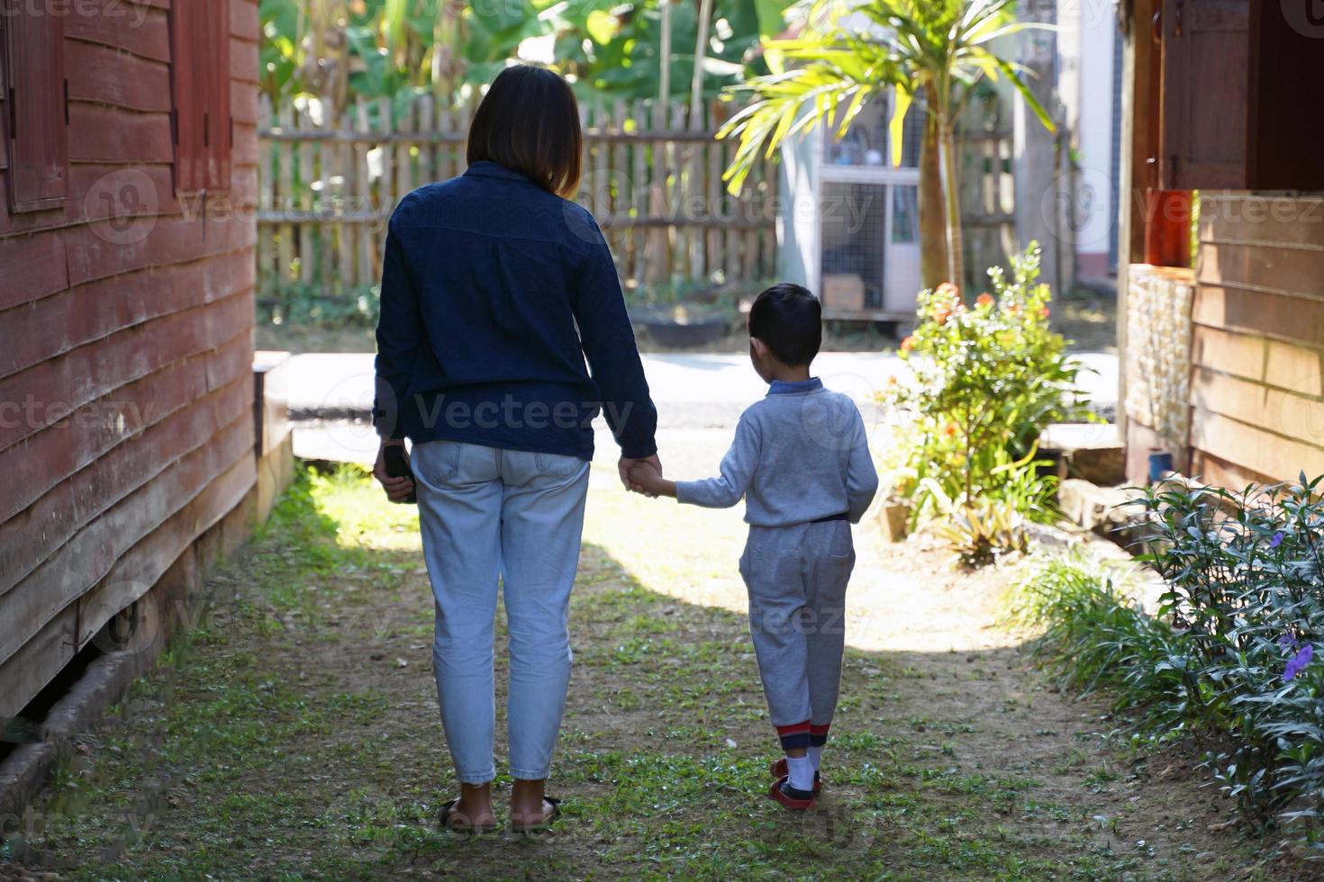 A mother walks by the hand of her son to walk outside the house. Soft and selective focus. photo