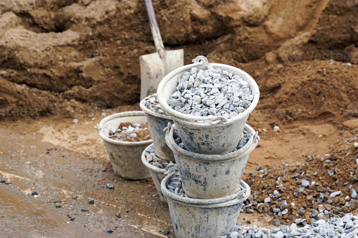 Stone buckets are stacked near the pile of sand to prepare for mixing with cement and other aggregates in the mortar mixer. soft and selective focus. photo