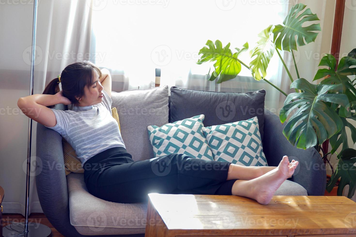 Asian woman lay down and relax on the sofa She propped her legs up