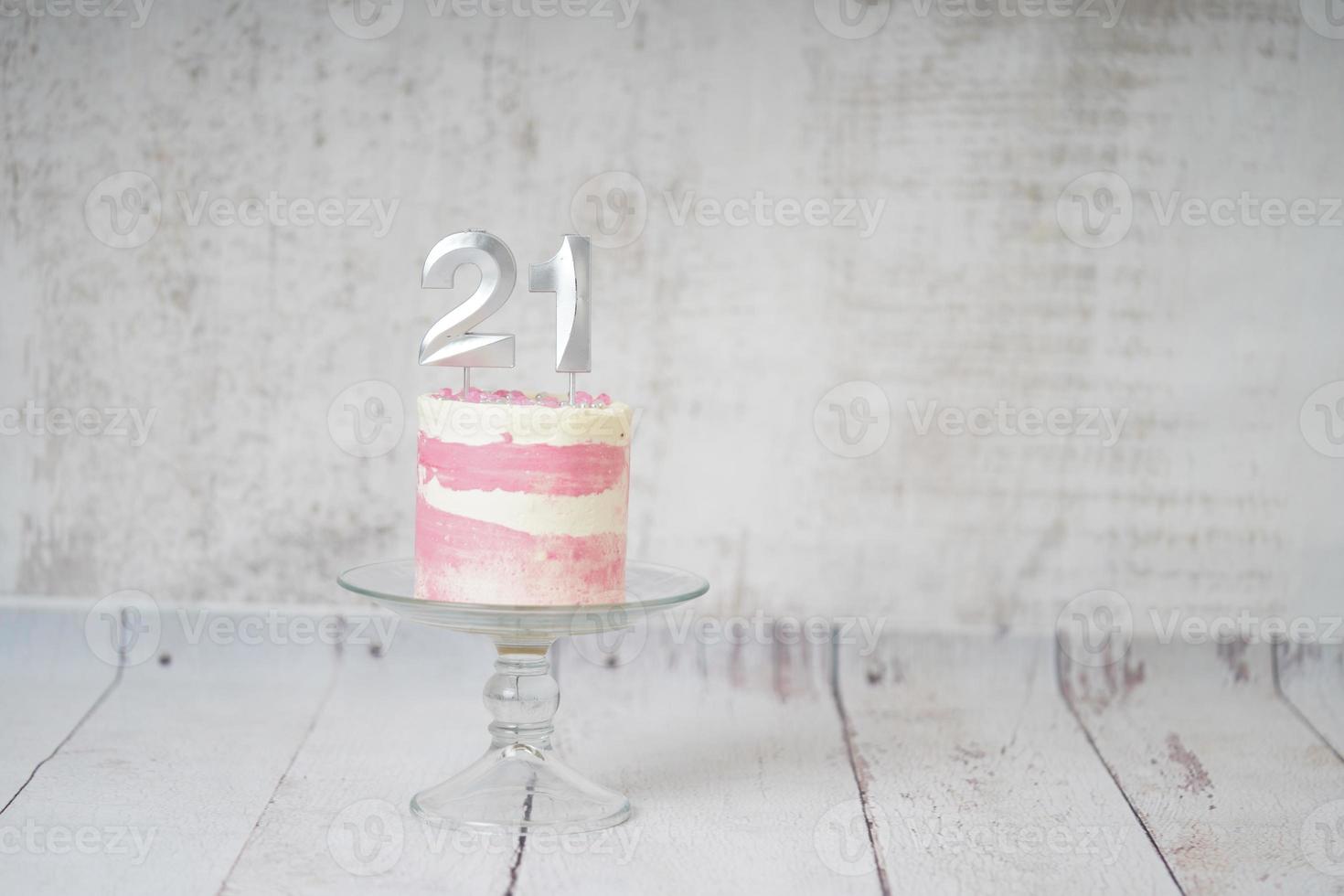 21st Birthday cake pink and silver cake with some sprinkles and 21st candlelight on a white wooden background. photo