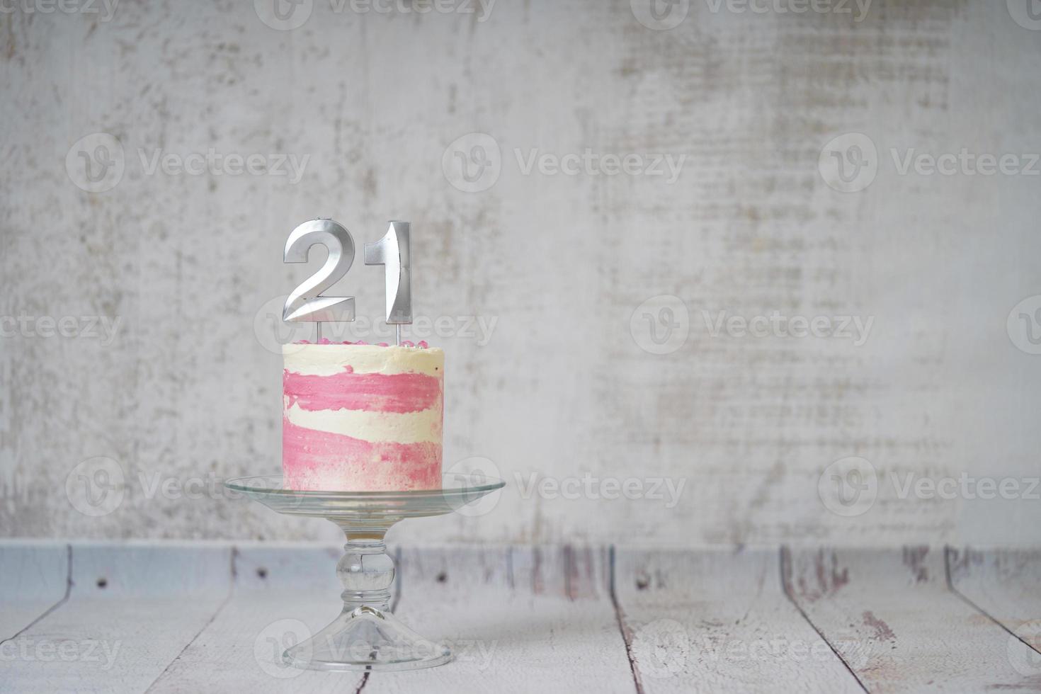 21st Birthday cake pink and silver cake with some sprinkles and 21st candlelight on a white wooden background. photo