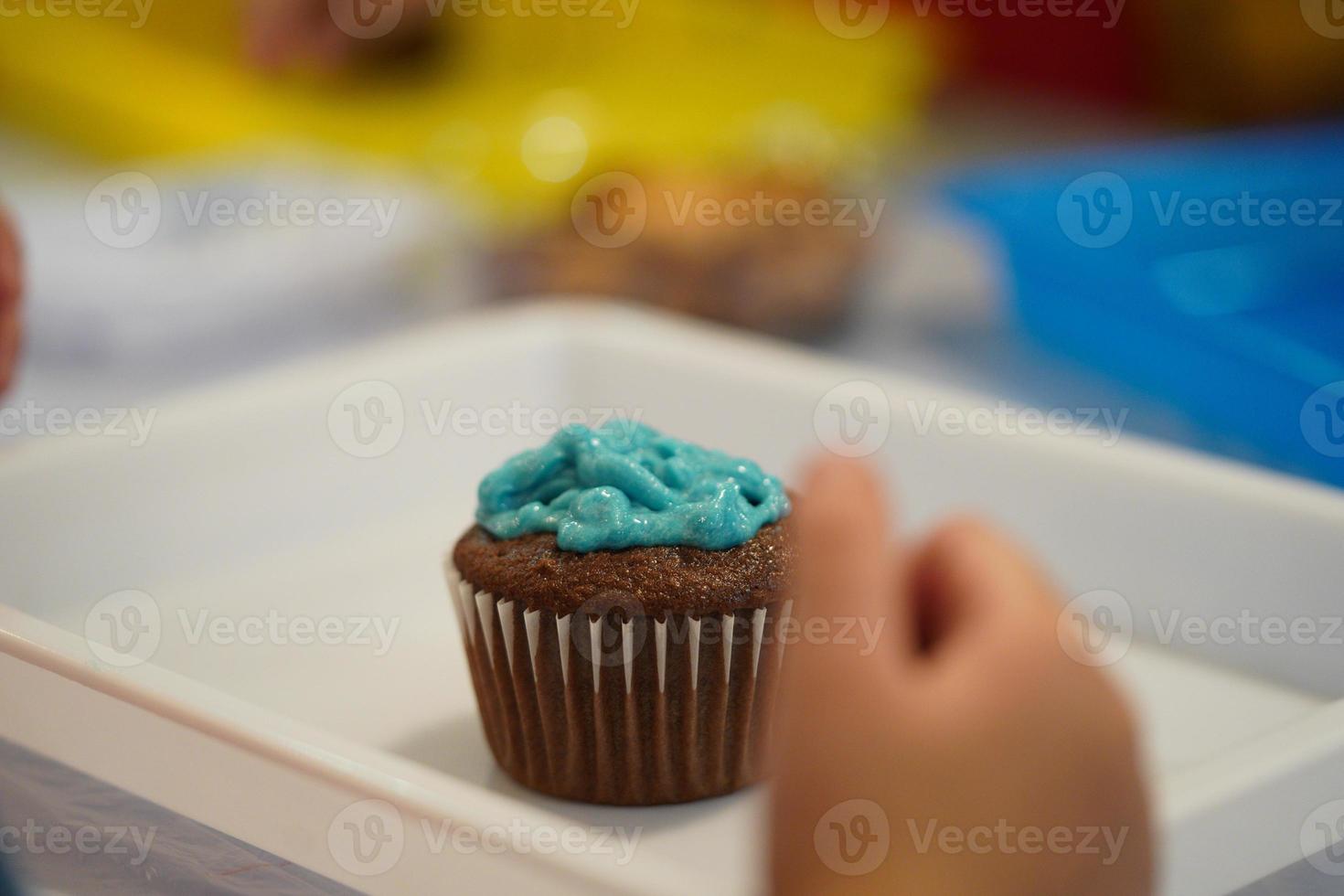 kid crafts decorating cakes. decorating a chocolate cupcake with blue frosting. photo