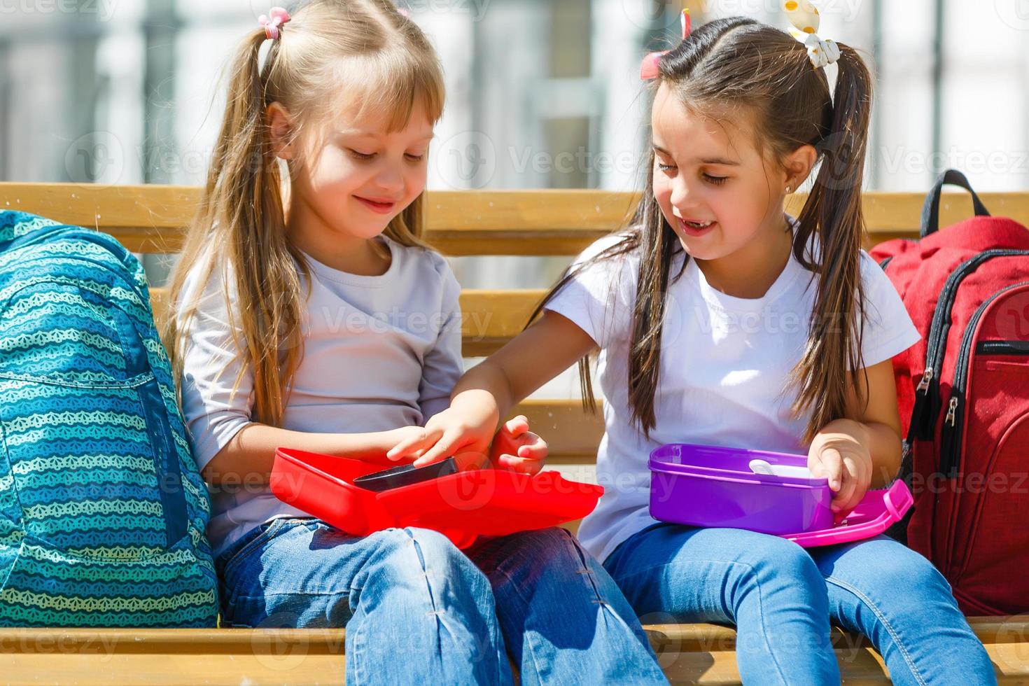 niños de escuela primaria sentados con almuerzos para llevar foto