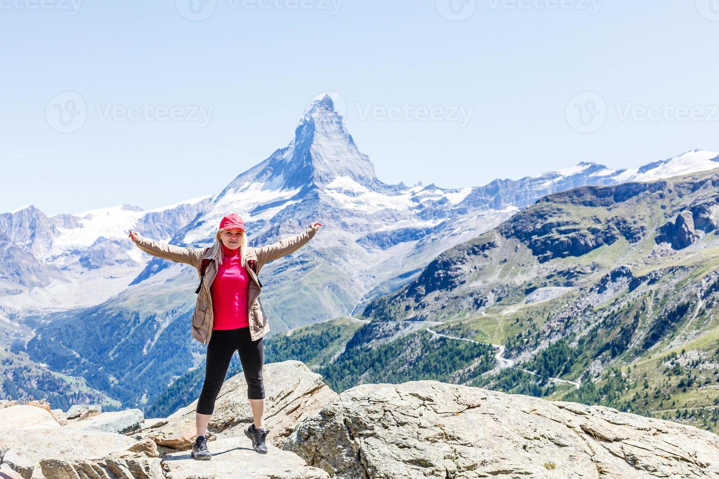 Woman on mountain top of mountain landscape around lake and blue sky. photo