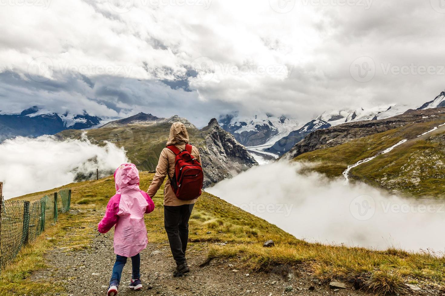 Hikers with backpack looking at mountains, alpine view, mother with child photo